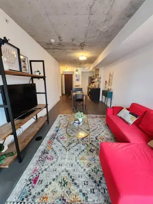 a living room with a red couch and a table at Chic 1BDR Loft with Office Space-Heart of Toronto in Toronto