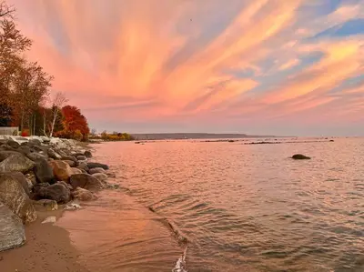 a body of water with rocks and a cloudy sky at New and Cozy Cottage Minutes to Blue Mountain in Meaford