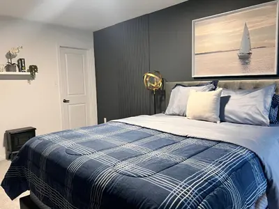 a bedroom with a bed with a blue and white blanket at Spacious 4-Bedroom Home, Comfortably Sleeps 10 in Barrie