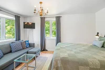 a bedroom with a bed and a couch and windows at Vineyard Villa in Niagara on the Lake