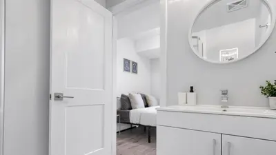 a white bathroom with a sink and a mirror at 2br Boho Townhouse - Walk To Falls, Free Parking in Niagara Falls