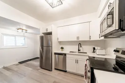 a kitchen with white cabinets and a stainless steel refrigerator at 2br - Spacious Yard - Canal Bridge, Falls Nearby! in Welland