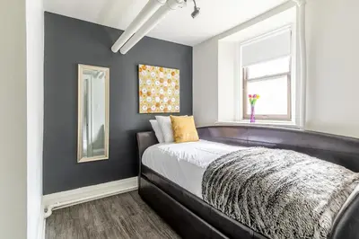a bedroom with a black bed and a window at Modern Apartment in a Trendy Neighbourhood in Hamilton