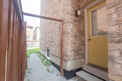a brick building with a yellow door next to a sidewalk at Main Floor Luxury Apartment in Vaughan