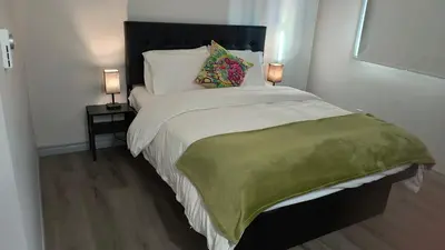 a bedroom with a bed with a green blanket and two lamps at SHORE VISTA LODGE in Georgina