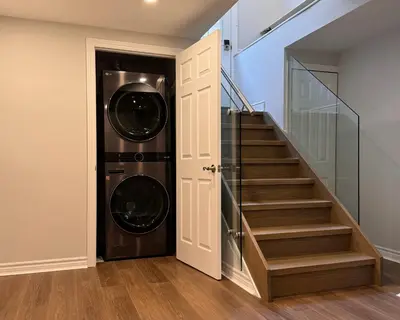 a laundry room with a washer and dryer next to a staircase at Spacious Bottom-Floor 2BR Suite in Innisfil