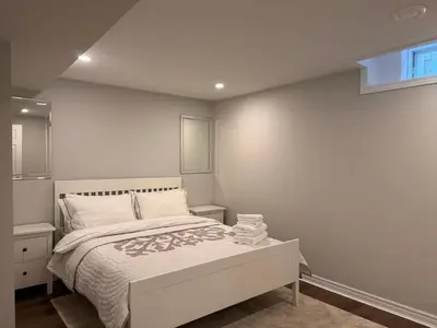 a white bedroom with a bed and a window at Spacious Bottom-Floor 2BR Suite in Innisfil
