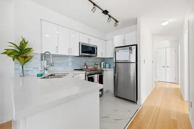 a kitchen with white cabinets and a stainless steel refrigerator at Modern 2-Bedroom Condo w Floor to Ceiling Windows in Toronto