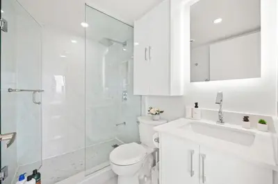 a white bathroom with a toilet and a shower at Modern 2-Bedroom Condo w Floor to Ceiling Windows in Toronto