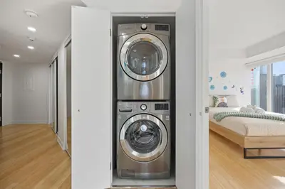 a washer and dryer in a room with a bed at Modern 2-Bedroom Condo w Floor to Ceiling Windows in Toronto