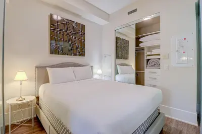 a white bedroom with a bed and a mirror at Metropolis Loft - CN Tower in Toronto