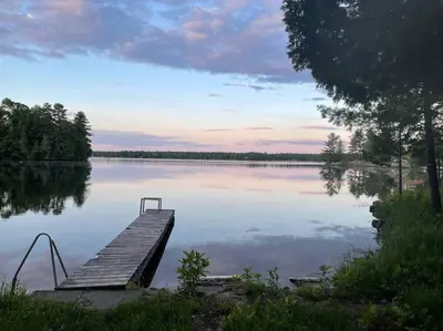 a dock on a lake with the sun setting at Gorgeous Muskokan Cottage on Six Mile Lake in Port Severn