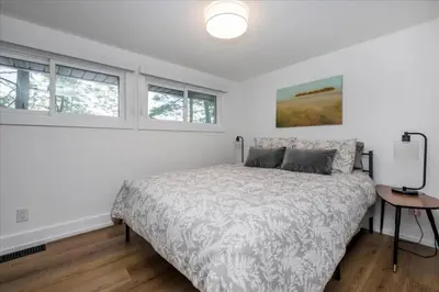a bedroom with a bed and two windows at Gorgeous Muskokan Cottage on Six Mile Lake in Port Severn