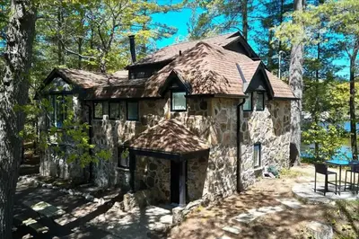 a cabin in the woods with a shingled roof at Gorgeous Muskokan Cottage on Six Mile Lake in Port Severn