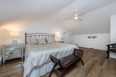 a white bedroom with a bed and a chair at Gorgeous Muskokan Cottage on Six Mile Lake in Port Severn