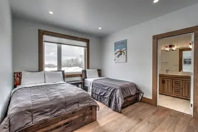 a bedroom with two beds and a sink and a mirror at Luxury Cottage at Blue Mountain, Private Beach Access, BBQ, Hot Tub, 7 baths in Blue Mountains