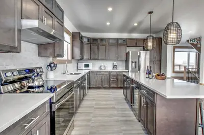 a large kitchen with stainless steel appliances and wood cabinets at Luxury Cottage at Blue Mountain, Private Beach Access, BBQ, Hot Tub, 7 baths in Blue Mountains