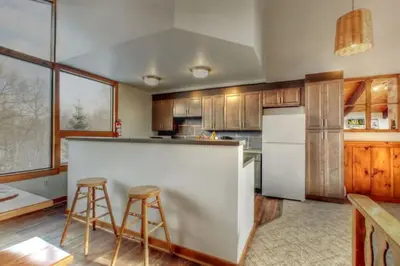a kitchen with a counter and two bar stools at 8 bdrm Blue Mountain Cottage, Large Groups, Private Beach Access, Hot Tub, Sauna, Ping Pong Table Perfect for Large Groups, Petfriendly in Blue Mountains