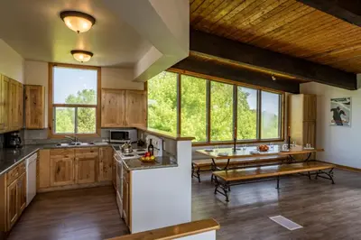 a large kitchen with wooden cabinets and a table at 6 bdrm Blue Mountain Cottage, Private Beach Access, Hot Tub, Sauna, Table Tennis, BBQ, Petfriendly in Blue Mountains