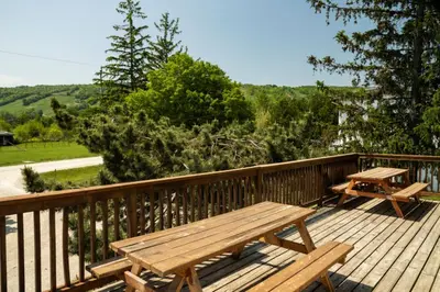 a wooden deck with two picnic tables on it at 6 bdrm Blue Mountain Cottage, Private Beach Access, Hot Tub, Sauna, Table Tennis, BBQ, Petfriendly in Blue Mountains
