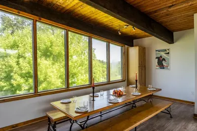 a dining room with a table and some windows at 6 bdrm Blue Mountain Cottage, Private Beach Access, Hot Tub, Sauna, Table Tennis, BBQ, Petfriendly in Blue Mountains