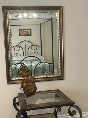 a mirror on a wall with a table and a bed at Khan’s Resort in Cobourg