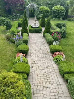 a brick path in a garden with bushes and a fountain at Khan’s Resort in Cobourg