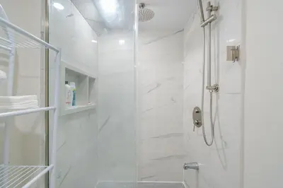 a white bathroom with a shower with a glass door at Cozy basement suites Oakville in Oakville