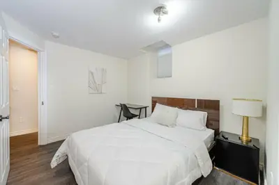 a white bedroom with a bed and a lamp at Cozy basement suites Oakville in Oakville