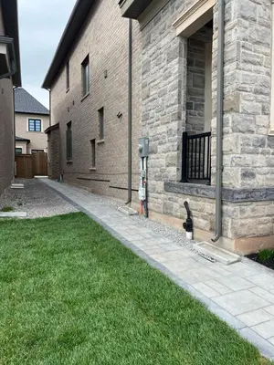 a cat is sitting next to a brick building at Cozy basement suites Oakville in Oakville