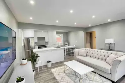 a living room with a couch and a kitchen at White House Suite - Sleeps 4 in St. Catharines