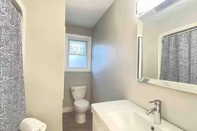 a bathroom with a toilet and a sink and a mirror at White House Suite - Sleeps 4 in St. Catharines