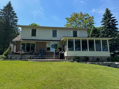 a house with a screened in porch on a lawn at The Captains Lake House in Orillia