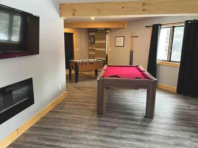 a room with a ping pong table in a room at Lovely Muskoka Waterfront Cottage-Hot tub & Sauna! in Bracebridge