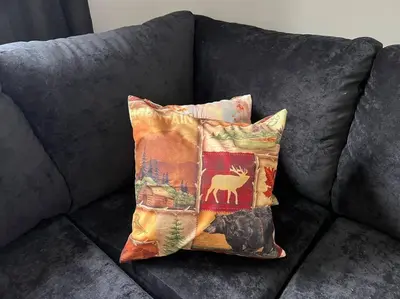 a couch with two pillows with a deer on it at Lovely Muskoka Waterfront Cottage-Hot tub & Sauna! in Bracebridge
