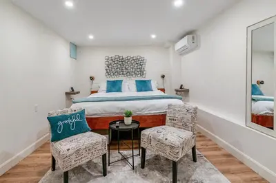 a bedroom with a bed with blue pillows and two chairs at Historic Victorian with Deck and Parking in Toronto