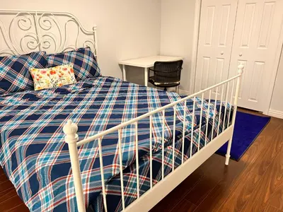 a white bed with a blue plaid blanket and a table at 3 BR GREAT HOUSE WITH ONE parking in Richmond Hill