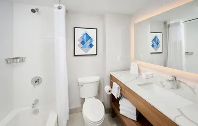a bathroom with a toilet and a tub and a sink at Candlewood Suites Burlington Conference Centre by IHG in Burlington