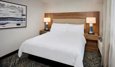 a hotel room with a white bed and two lamps at Candlewood Suites Burlington Conference Centre by IHG in Burlington