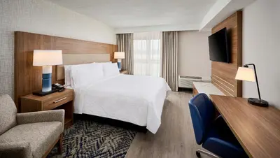 a hotel room with a bed and a chair at Candlewood Suites Burlington Conference Centre by IHG in Burlington