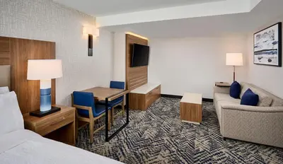 a hotel room with a bed and a desk and a couch at Candlewood Suites Burlington Conference Centre by IHG in Burlington