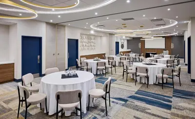 a dining room with tables and chairs and a screen at Candlewood Suites Burlington Conference Centre by IHG in Burlington