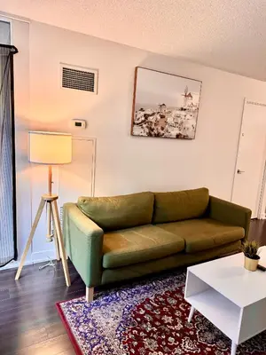 a living room with a green couch and a table at Lush Condo By CNTower - Free Parking in Toronto
