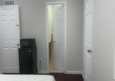 a bedroom with two white doors and a black refrigerator at Beautiful private Room near Toronto pearson Airport in Brampton