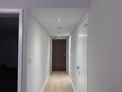 a hallway with white walls and a wooden door at Downtown 2 bedroom Gem with Free Parking in Toronto