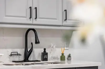 a kitchen counter with a sink and white cabinets at Urban Haven: 2BR/2BA+Office, Kitchen, Dining in Newcastle