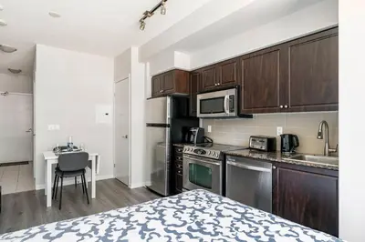 a kitchen with stainless steel appliances and a table at Luxury Suites Steps to CN Tower - Lock in 4 Weeks Enjoy Half OFF in Toronto