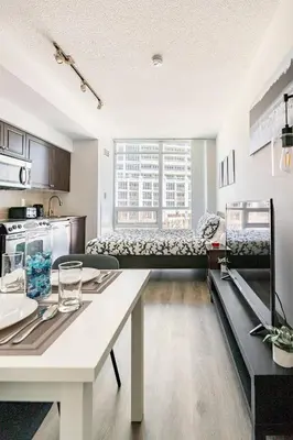 a kitchen and a living room with a table at Luxury Suites Steps to CN Tower - Lock in 4 Weeks Enjoy Half OFF in Toronto