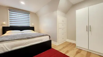 a bedroom with a large bed and a red rug at The Serene Haven Modern 2 Queen Bed Full Apartment in St. Catharines