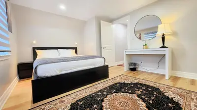 a bedroom with a bed and a mirror and a rug at The Serene Haven Modern 2 Queen Bed Full Apartment in St. Catharines
